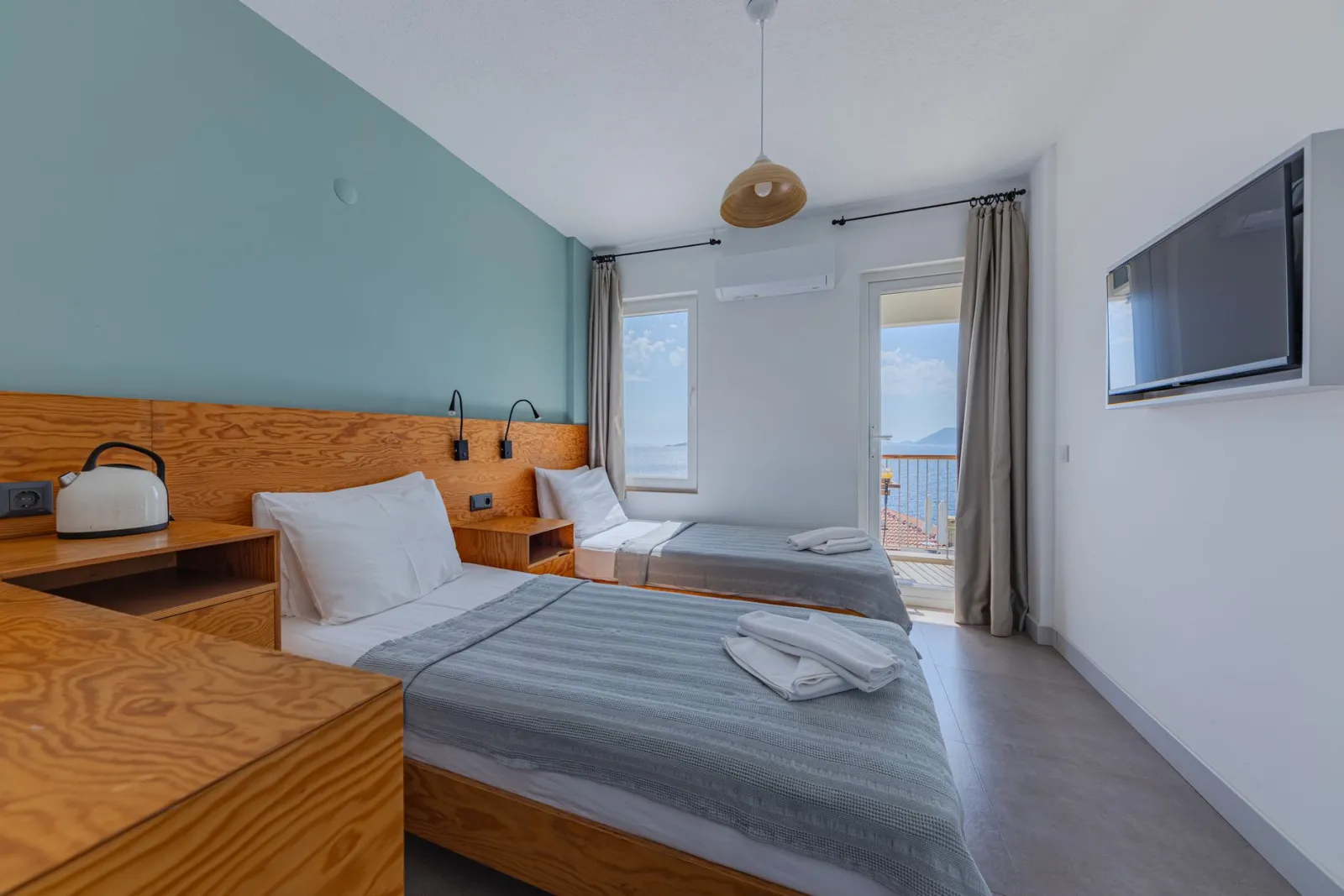 Bright hotel room featuring twin beds, modern decor, and a stunning sea view.